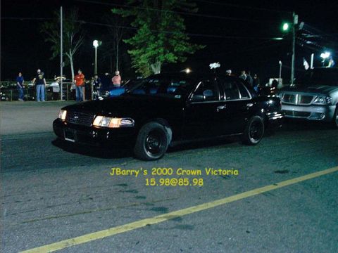 2000 Ford Crown Victoria - Night shot of a black 2000 Ford Crown Victoria on a track with another vehicle nearby.