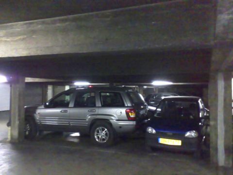 1991 Ford LTD Crown Victoria - A silver SUV is parked next to a dark blue hatchback in a dimly lit parking garage.