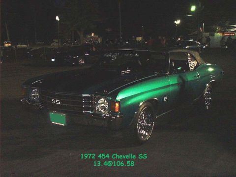 2000 Ford Crown Victoria - A green convertible muscle car is parked at an outdoor event at night, with people and other vehicles in the background.