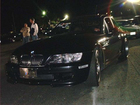 2000 Ford Crown Victoria - Black BMW Z3 coupe at a nighttime event, with other vehicles visible in the background.