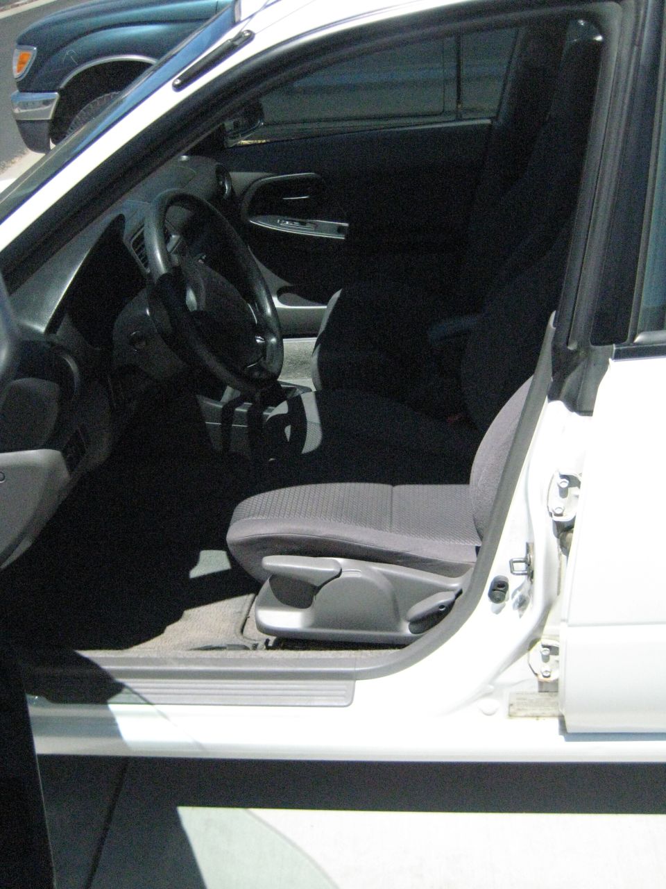 White pickup truck interior with gray cloth seats and black dashboard. Another dark colored vehicle is visible outside