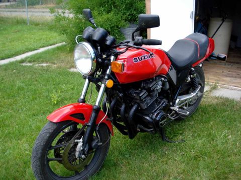2008 Ford Crown Victoria - A red Suzuki motorcycle is parked on a grassy area next to a building.