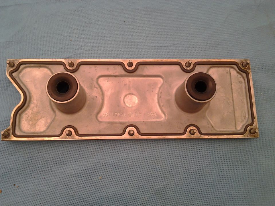 Silver engine part with two rubber grommets and visible text