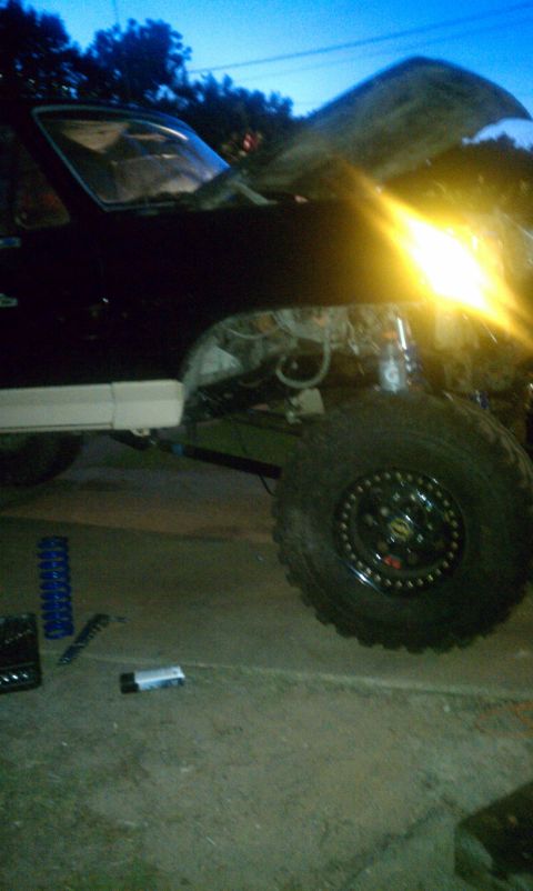 1990 Ford Bronco - This 1990 Ford Bronco is being worked on, with its hood up and a bright headlight illuminating the scene.