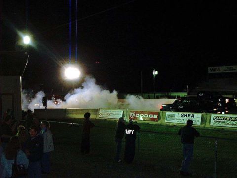 2000 Ford Crown Victoria - A car performs a burnout on the drag strip at night, creating a large cloud of smoke.