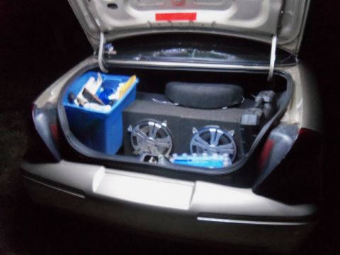 2000 Mercury Grand Marquis - The trunk of a car is open, revealing a blue storage bin, a spare tire, and a large speaker system.