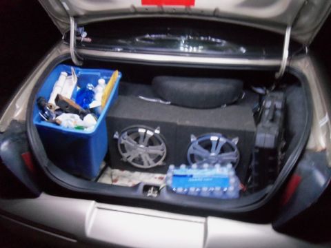 2000 Mercury Grand Marquis - The trunk of a car contains a blue storage bin, a subwoofer, and a spare tire.