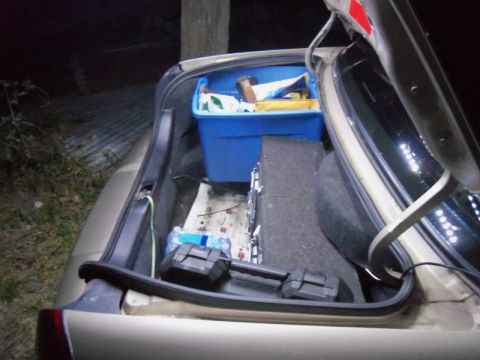 2000 Mercury Grand Marquis - The open trunk of a car contains a blue storage bin, a speaker, and water bottles.