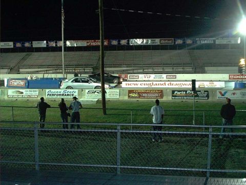 2000 Ford Crown Victoria - Spectators observe a drag race event at New England Dragway under the night sky.