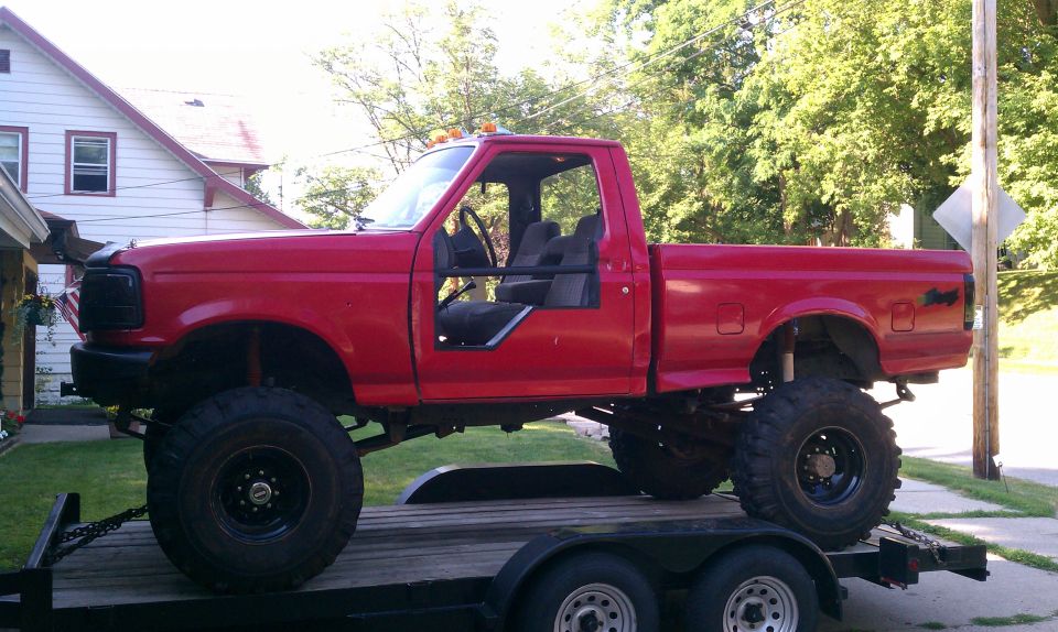 Red 1994 Ford F-250 pickup truck with lifted suspension and large tires