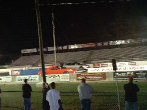 2000 Ford Crown Victoria - Night drag racing event at New England Dragway with spectators in the stands.