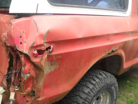 1993 Ford F-150 - This red SUV shows extensive damage to its rear, including rust and a missing taillight. The body style suggests an older model.