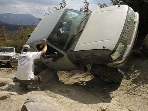 1997 Ford Ranger - An off-road truck is stuck on a rocky incline, with a person observing the situation.