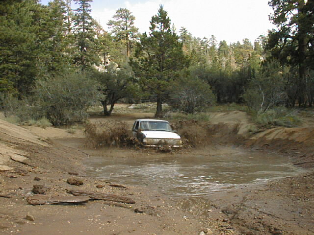 1997 Ford Ranger splashing through a muddy puddle on a dirt road