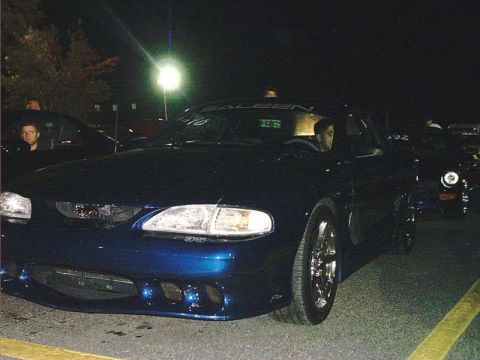 2000 Ford Crown Victoria - Front view of a dark blue Ford Mustang, possibly a Saleen model, at night.