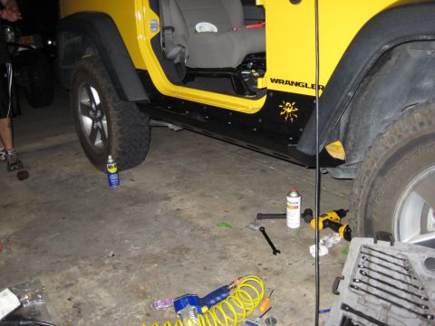2005 Jeep Wrangler - A yellow Jeep Wrangler is parked indoors with various tools and spray cans scattered around it.