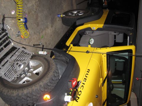 2005 Jeep Wrangler - A yellow Jeep Wrangler Rubicon is parked in a garage with tools and equipment nearby.
