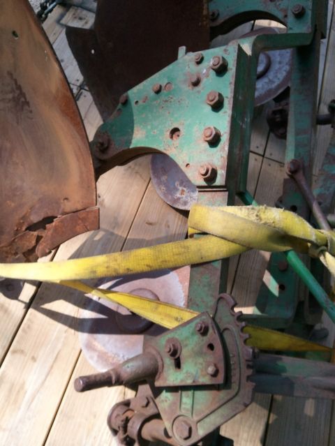 1985 Ford F-150 - Close-up view of a rusty agricultural plow mechanism secured with yellow straps.