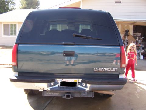 1995 Chevrolet Tahoe - The rear of a dark green Chevrolet Tahoe is shown, with a young girl in red standing to the right.