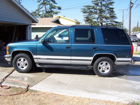 1995 Chevrolet Tahoe - A teal 1995 Chevrolet Tahoe SUV is parked on a concrete driveway next to a garage.
