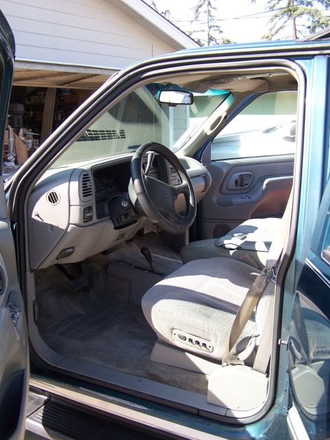 1995 Chevrolet Tahoe - The interior of a teal SUV is visible with the driver's side door open, revealing the dashboard and seats.