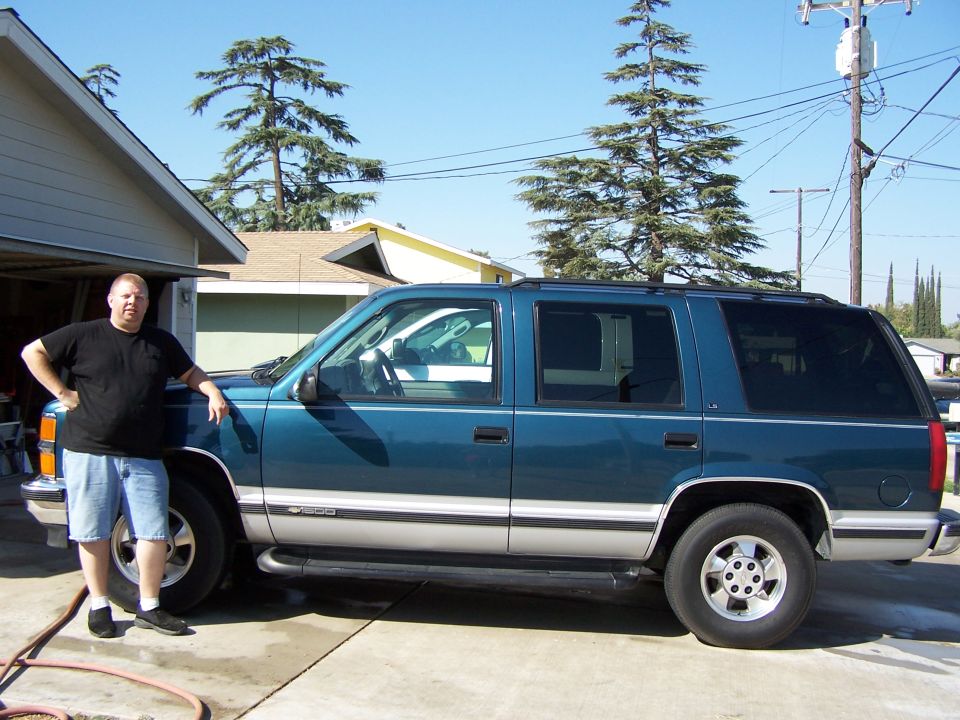 Teal and silver 1995 Chevrolet Tahoe SUV parked on a concrete driveway, side view
