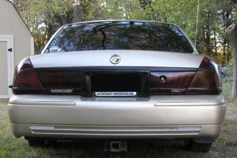 2000 Mercury Grand Marquis - The rear of a gold Mercury Grand Marquis is shown with tinted taillights and a trailer hitch.