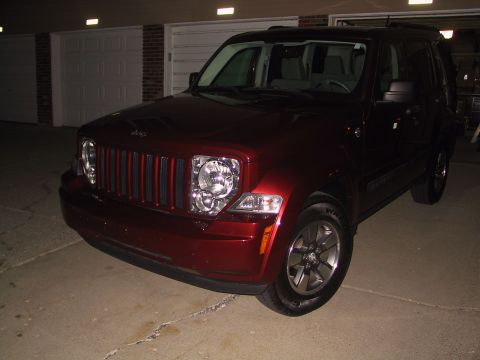 2008 Jeep Liberty - A red 2008 Jeep Liberty is shown from a three-quarter front angle in front of a garage.