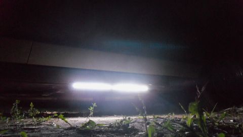2000 Mercury Grand Marquis - The underside of a vehicle is illuminated by two bright lights, with some vegetation visible below.