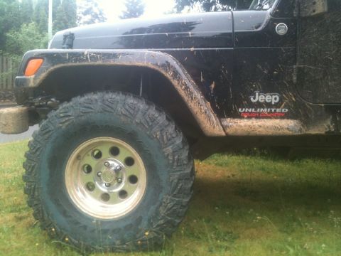 2005 Jeep Wrangler - Mud-splattered black 2005 Jeep Wrangler Unlimited Rough Country shows off its off-road tires and fender flares.