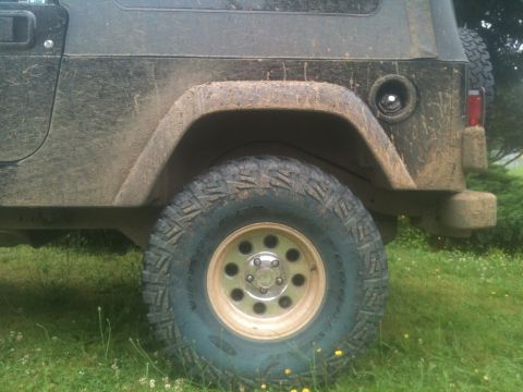 2005 Jeep Wrangler - Rear view of a muddy 2005 Jeep Wrangler showing the tire and quarter panel.