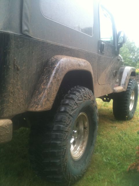 2005 Jeep Wrangler - Side view of a muddy Jeep Wrangler with off-road tires and a soft top.