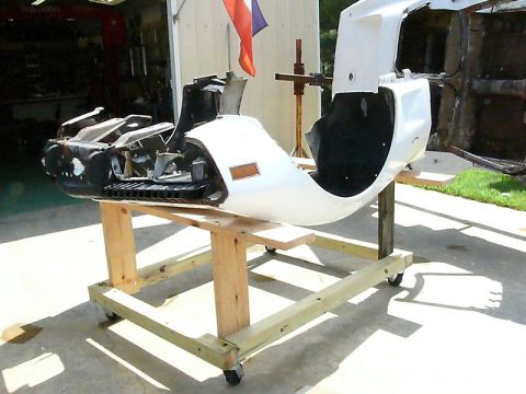 1976 Chevrolet Corvette - A white car body section, likely a front clip, is mounted on a wooden stand for repair or display.