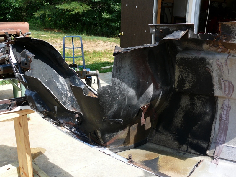 car frame and body panels on sawhorses outside a garage