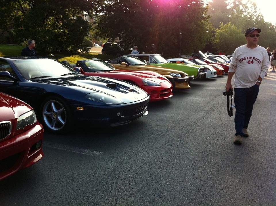Several sports cars parked in a line, with a man walking past them