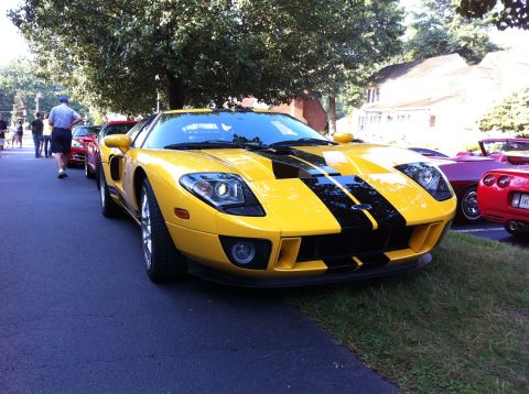 2010 Ford Falcon - A bright yellow 2005 Ford GT with black racing stripes is parked on the side of the road, with other cars visible in the background.