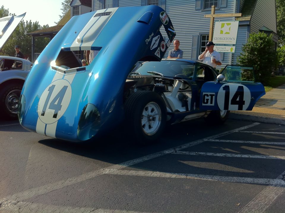 blue and white race car with number 14 on door and hood open, another car visible to the left