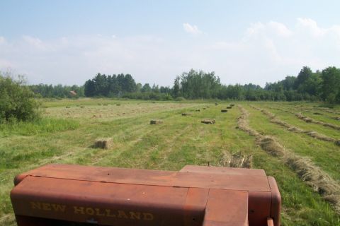 2000 Chevrolet Tahoe - A tractor operates in a field, baling hay under a clear sky.