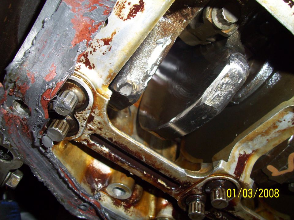 Engine block interior with crankshaft, showing oil residue and metal damage