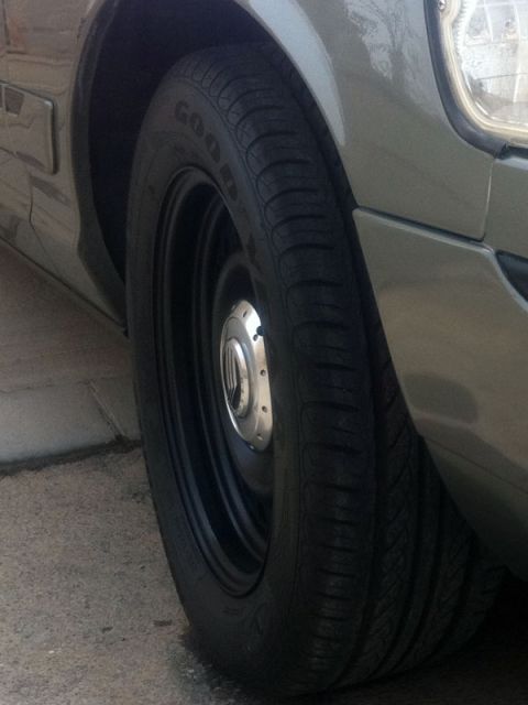 2001 Mercury Grand Marquis - Close-up of the front wheel and tire assembly on a gray 2001 Mercury Grand Marquis.