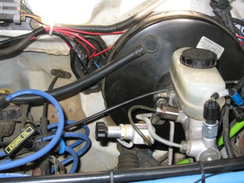 1995 Ford Bronco - Close-up of a brake master cylinder and booster assembly, with blue spark plug wires visible.