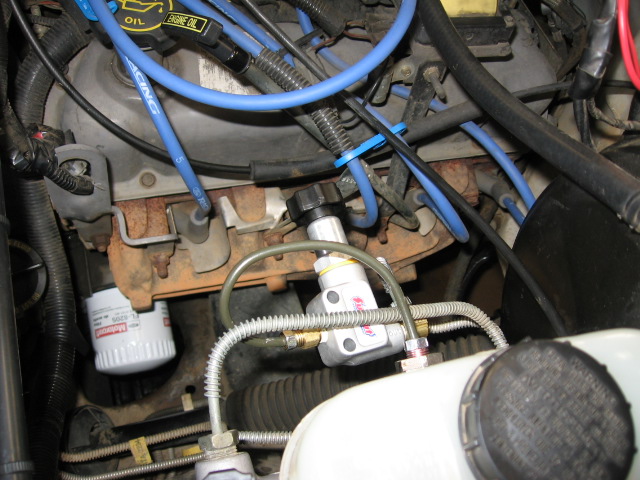 Adjustable brake proportioning valve with braided lines installed in an engine bay near the master cylinder
