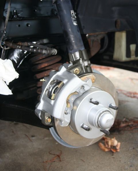 1980 Ford Mustang - Close-up of a vehicle's front brake assembly, including caliper, rotor, and shock absorber.