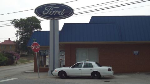 1998 Ford Crown Victoria - White 1998 Ford Crown Victoria taxi parked by a Ford dealership with a large Ford sign.