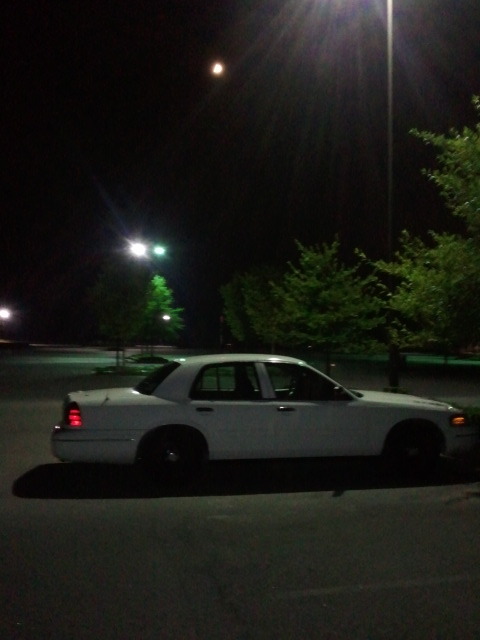 1998 Ford Crown Victoria - A white 1998 Ford Crown Victoria is parked in a lot at night under streetlights.