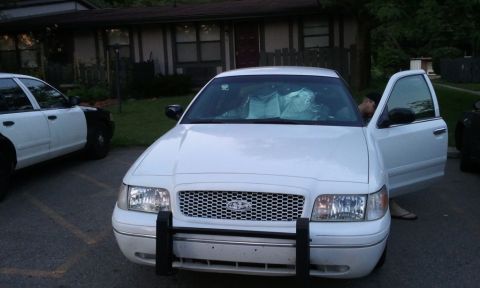 1998 Ford Crown Victoria - A white 1998 Ford Crown Victoria is seen from the front, parked next to another vehicle, with the driver's door ajar.