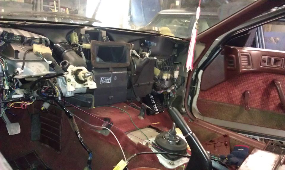 1987 Mazda RX-7 interior with dashboard removed, showing wiring and components