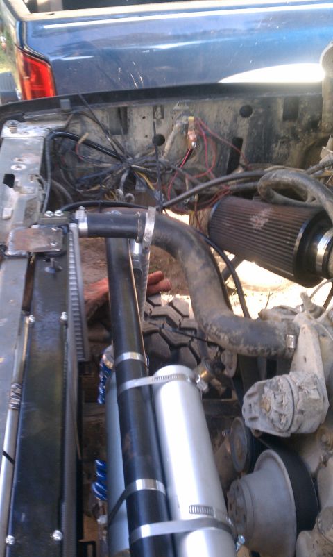 1990 Ford Bronco - Engine bay details, including an aftermarket air filter and various hoses. A blue vehicle is visible in the background.