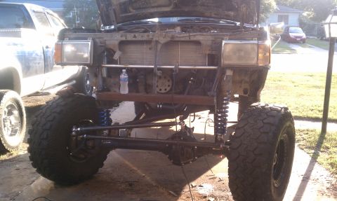 1990 Ford Bronco - Front view of a modified 1990 Ford Bronco with its hood up and suspension lifted.