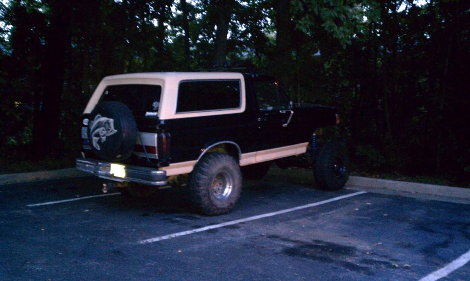 Rear view of a lifted black and tan Ford Bronco with a spare tire mounted on the tailgate